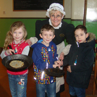 Children with Mrs Hales in Palace House. Taking part in the pancake tossing competition.