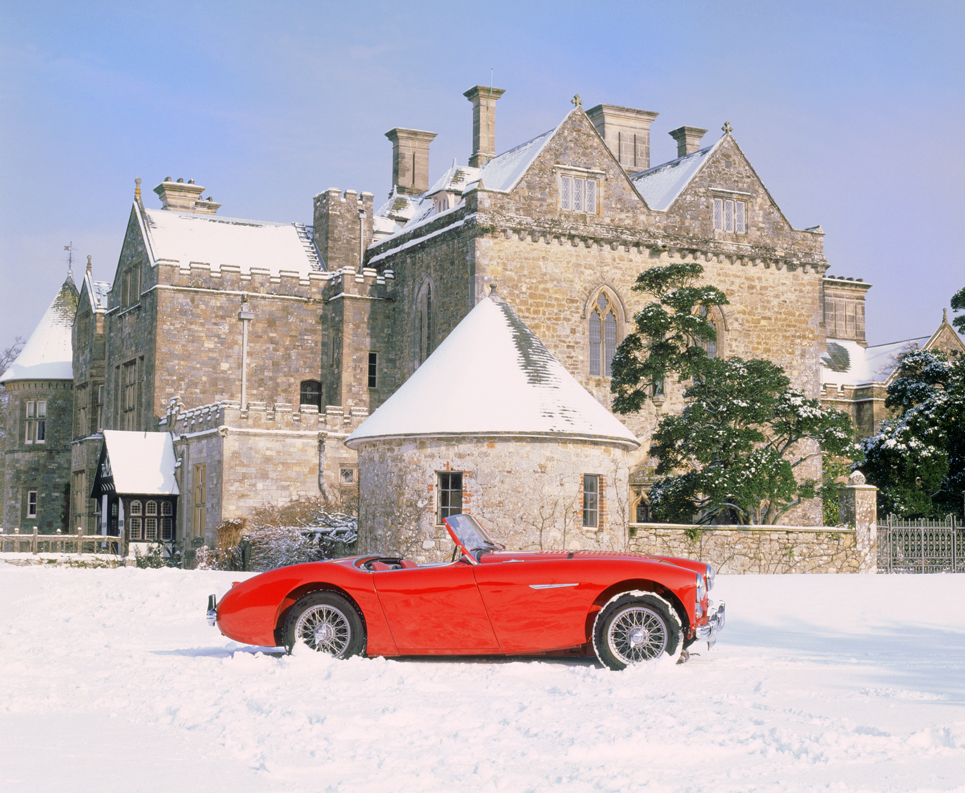 1956 Austin Healey 100 in front of Palace House at Beaulieu in the snow.