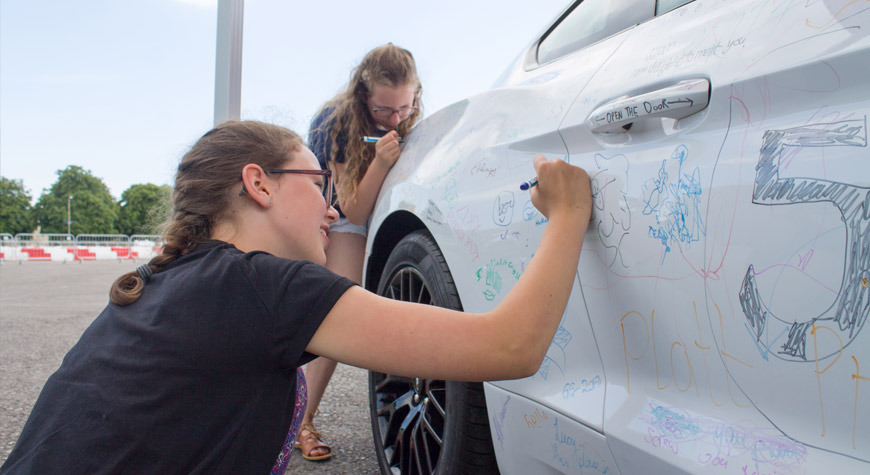 Two children draw on the Ford Mustang on the Beaulieu arena